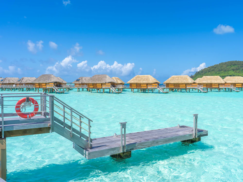 Muelle sobre una laguna turquesa con villas sobre el agua, en Bora Bora