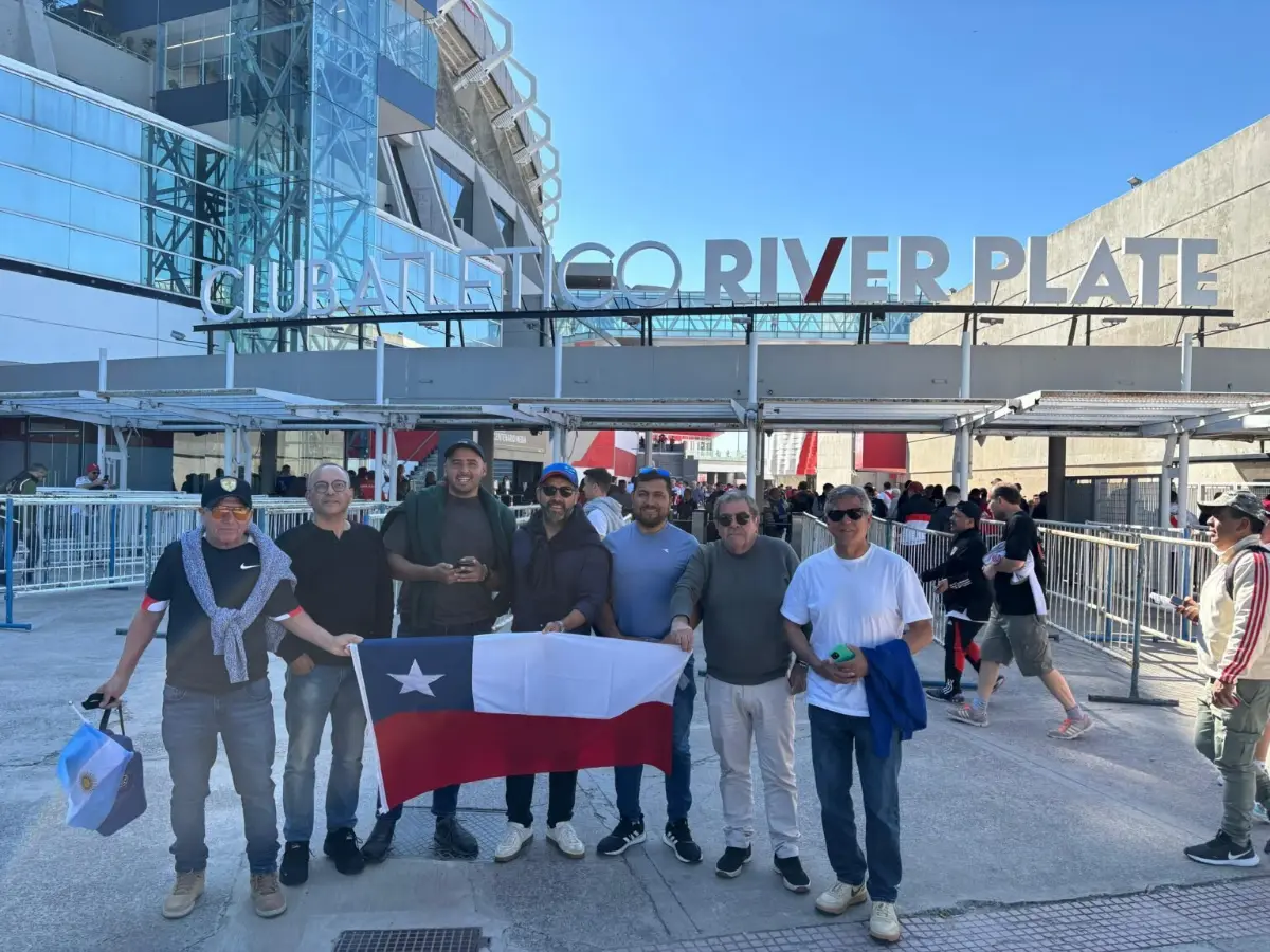 Grupo de viajeros con una bandera de Chile frente al estadio de River Plate